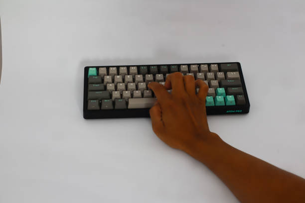 istock Close-up of Hand Typing on Black and Teal Atom Pro Keyboard on White Surface 2197346657