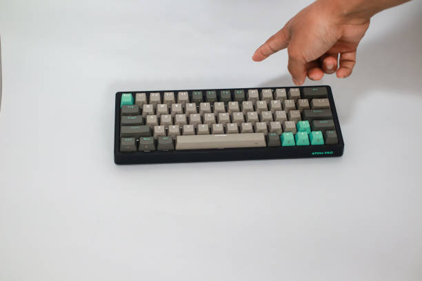 istock A hand reaches towards a black keyboard with light gray and mint green keys on a white surface 2197346679