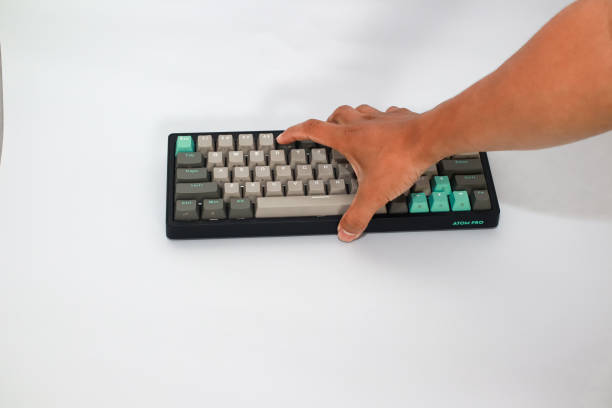 istock A hand presses keys on a black Atom Pro keyboard with grey and teal keycaps 2197346709