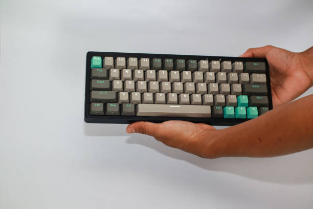 istock A person's hands hold a black keyboard with gray and teal keycaps against a white background 2197347035
