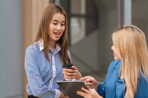istock Diverse women engaging in a discussion while holding coffee and a tablet. 2197347755