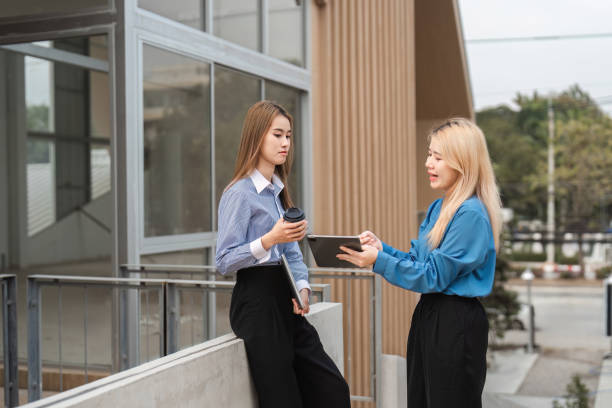 istock Diverse businesswomen collaborating while discussing ideas with a tablet and coffee outdoors. 2197347767