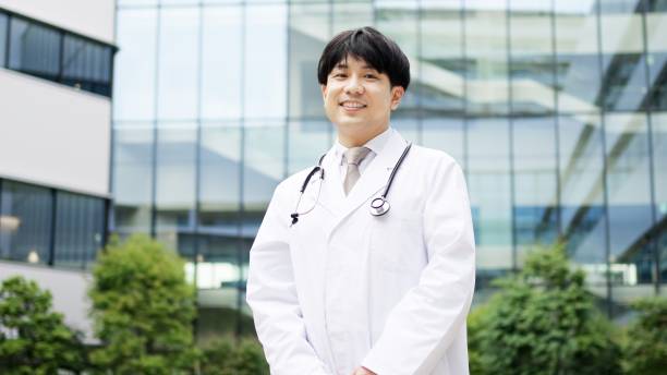 Smiling Asian male doctor standing stock photo