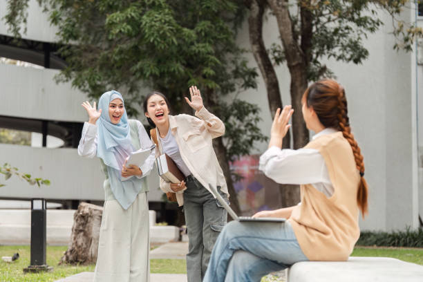 istock Diverse female students waving cheerfully at a friend on campus. 2197348868
