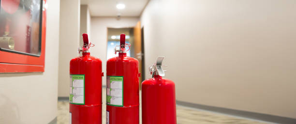 istock Close-up the red fire extinguishers tank at the exit door in the building concepts for emergency safety fire prevention rescue and fire services. 2197350600