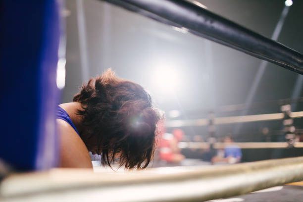 A female boxer hangs her head down after losing a boxing match.