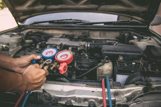 istock Auto mechanic using measuring equipment tool for filling old car air conditioners fix checking. Concepts of car care repair service and insurance. 2197351509