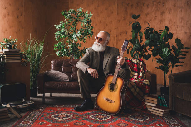 A stylish elderly gentleman seated indoors with a guitar, in a vintage-style environment featuring greenery, books, and a warm retro interior, evoking elegance and tapping into a nostalgic atmosphere