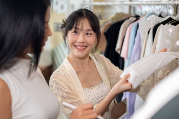 istock A customer is friendly asking for advice from a shop employee while selecting a dress to buy. 2197352283