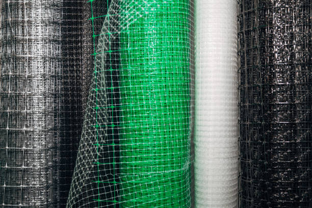 Protective white mesh sleeve covering orange cylindrical part of industrial machinery showing production detail used in transport safety, packaging and mechanical equipment protection process