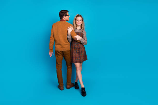 istock Young couple in retro style outfits posing on a vibrant blue background symbolizing friendship and casual fashion 2197356236