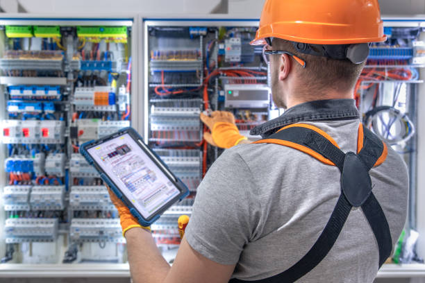 istock A male electrician in overalls, focused on work in switchboard with fuses, using tablet. 2197357391