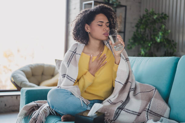 istock Young woman relaxing indoors while enjoying a drink, wrapped in a blanket 2197357778