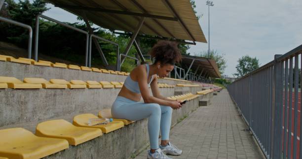 istock A woman uses a mobile phone at the stadium 2197359099