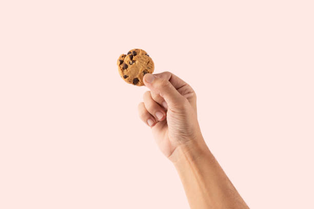 istock Male hand holding a cookie isolated on pink background 2197361206