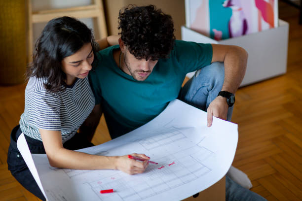 istock Young couple analyzing blueprint of new apartment while moving in 2197361957