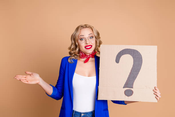 istock Confident Woman Holding Question Mark Sign on Beige Background 2197362104