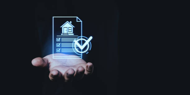 istock Hand holding a digital house checklist with a glowing checkmark on a dark background. 2197363939