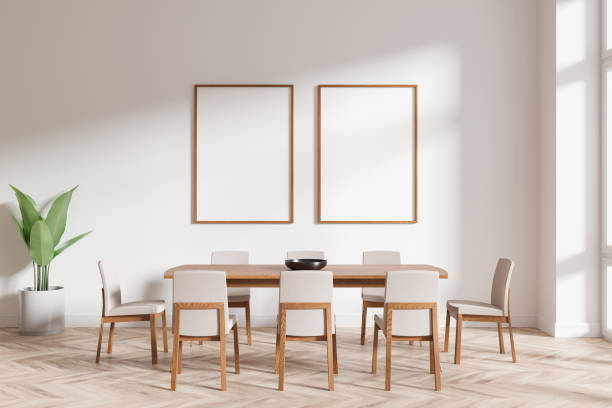 istock Minimalist dining room setting with wooden chairs, table, and two blank framed posters on the wall. Sunlight entering from the window. 3D Rendering 2197364056
