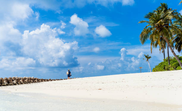 istock Back view of man in straw hat walking alone on white sandy beach on Maldives 2197366869