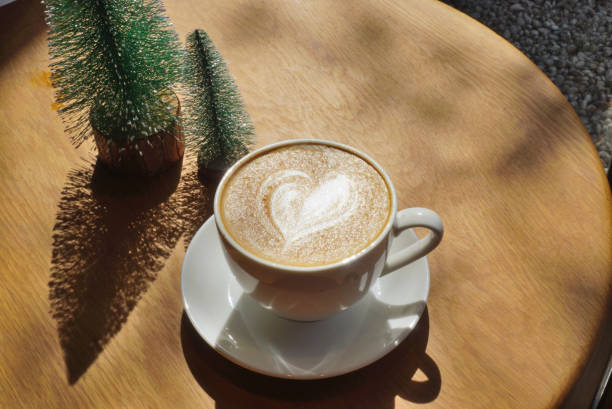 istock Latte art coffee cup on wooden table with pine tree decorative at beside 2197369392