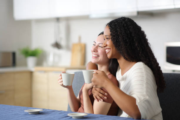 istock Happy interracial lesbian couple hugging and drinking coffee 2197369757