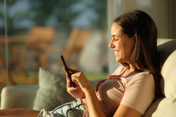 istock Happy woman using smart phone at sunset in a house 2197369914