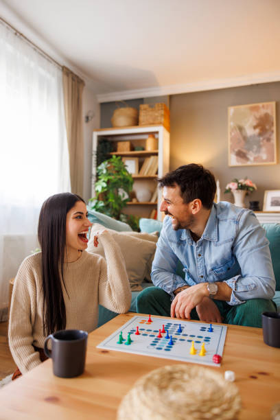 istock Beautiful young multi-ethnic couple in love playing ludo board game 2197370984
