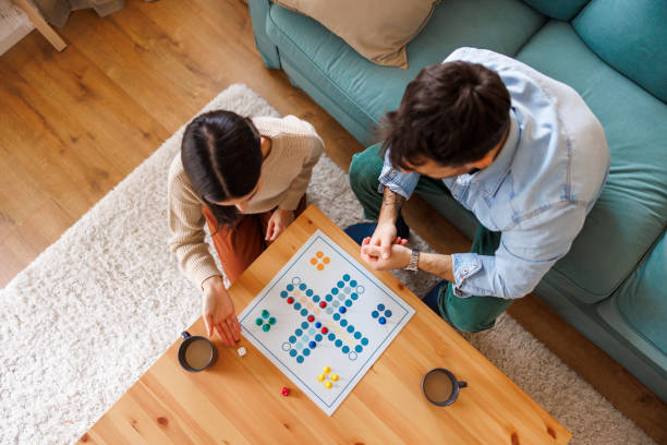 istock Couple having fun playing ludo board game while relaxing at home 2197371034