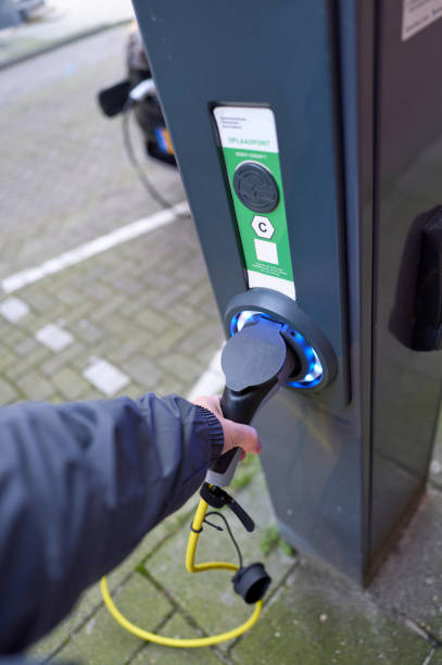 istock Driver connecting power cable to electric car charging station 2197374525