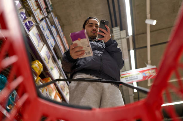 Young Man using smartphone while shopping in supermarket