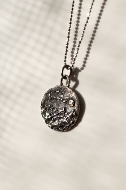 istock Handmade silver round pendant with a mountain range design on a white background with backlight. 2197377680