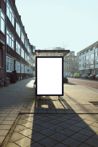 Empty white billboard next to a bus stop with the sun shining