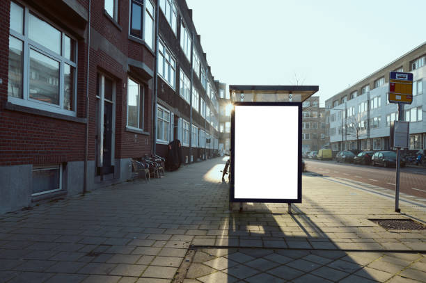 Blank white billboard standing next to a bus stop, advertising mockup