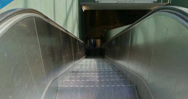 istock A woman rides up an escalator 2197381303