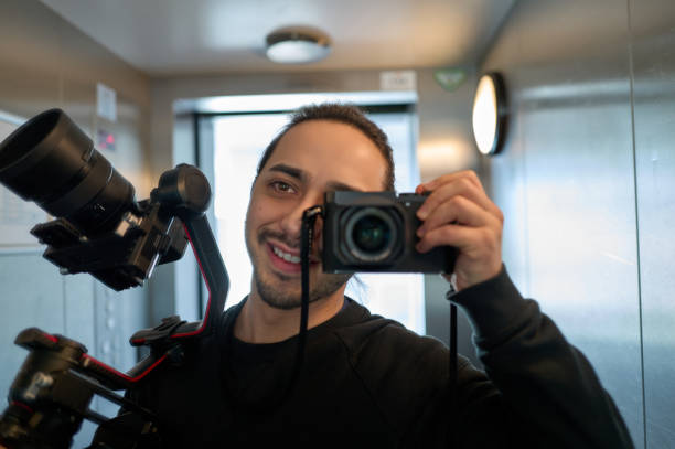 istock Videographer taking a selfie with a mirror in an elevator while holding a gimbal and a camera 2197381324