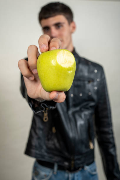 Musician showing a bitten green apple on a blurred background