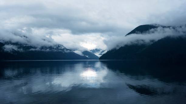 istock A serene lake with misty mountains reflecting in the water under a cloudy sky. 2197386487