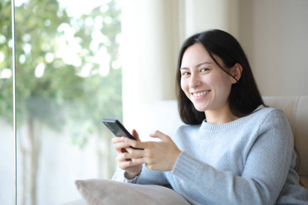 istock Happy asian woman using phone looking at camera at home 2197388255