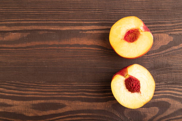Peach Cut in half on brown wooden background. Top view, flat lay, copy space. healthy food, vegetable, minimalism.