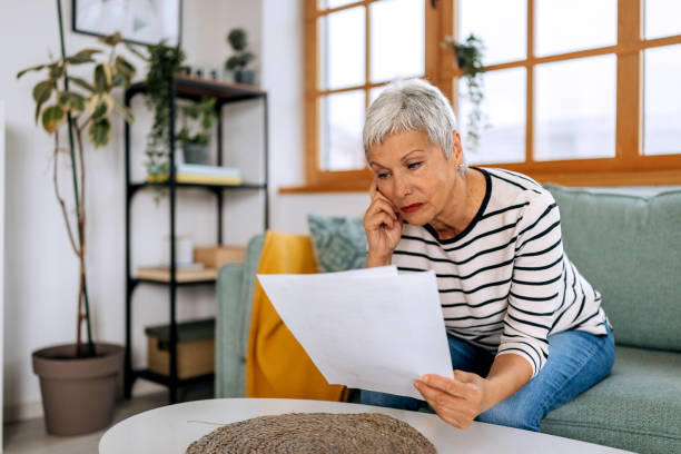 istock Senior woman going over bills at home 2197394494