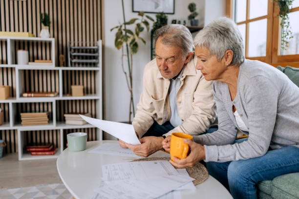 istock Senior couple examining bills while sitting on a sofa t home 2197394672