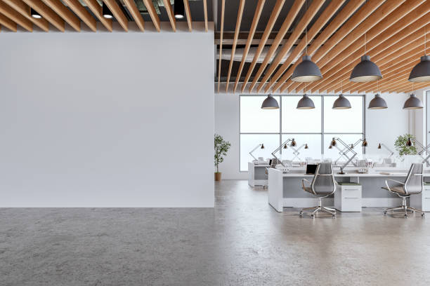 istock A modern office interior with large white wall and copy space,  a wooden slats ceiling, work desks and large windows, on concrete floor 2197399604