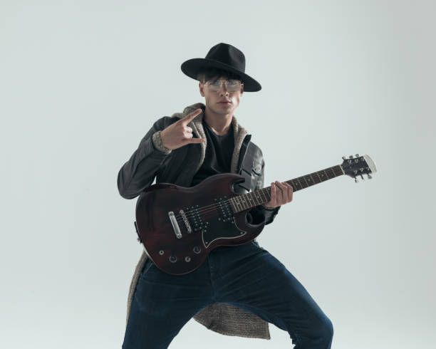 istock cool young man making rock and roll gesture while playing electric guitar 2197402166