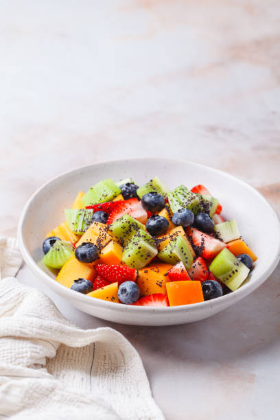 istock Fruit salad with kiwi, persimmon, berries and poppy seed dressing. 2197403325