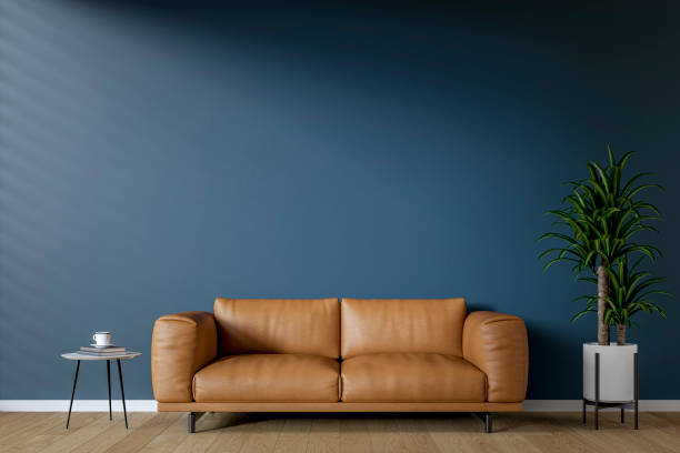 istock Modern interior: a living room with a brown sofa, low side table, deep blue plaster wall background and decoration 2197403812