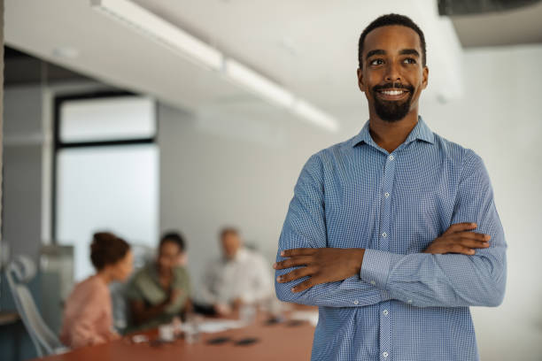 istock Man stands confidently in office with crossed arms. 2197403842