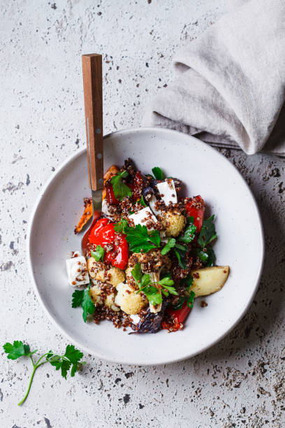 Warm quinoa salad with roasted vegetables and feta cheese, top view.
