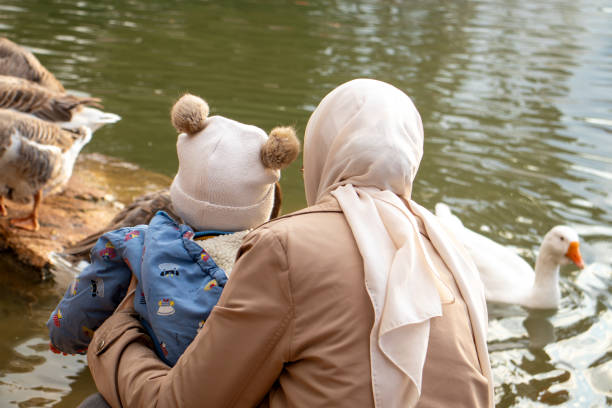 istock Mother and Child Interacting with Ducks by a Scenic Pond 2197405158