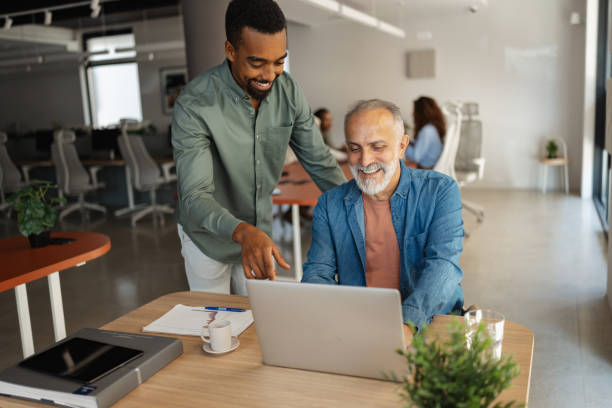 istock Two men smiling at laptop in a modern office setting. 2197407380